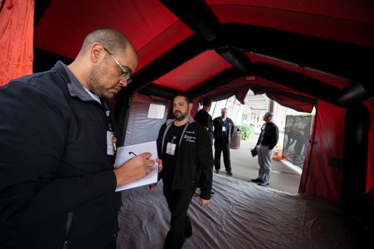 JPS Emergency Management team members inspect a COVID-19 screening tent.