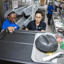 Dining Service Associate Symone Buckles, from left, and Nutritional Services Supervisor Jessica Contreras load trays of lunches for patients